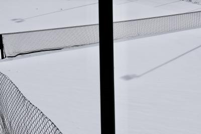 photograph “III.2024” par David Farreny — www.farreny.net — Andorre, Andorra, Canillo, tennis, court, neige, snow, hiver, winter, filet, net, clôture, fence, grillage, fencing, métal, metal, poteau, post, pole, ombres, shadows, lampadaires, lamps, vide, empty, emptiness