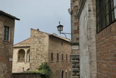 photograph “VIII.2022 — Via Talosa” par David Farreny — www.farreny.net — Italie, Italia, Italy, Toscane, Toscana, Tuscany, Sienne, Siena, Montepulciano, via Talosa, via Ricci già della Mercanzia, bâtiments, buildings, édifices, pierre, stone, brique, brick, lampe, lamp, fenêtres, windows, arches, arcs, archs, toits, roofs, coin, corner, angle