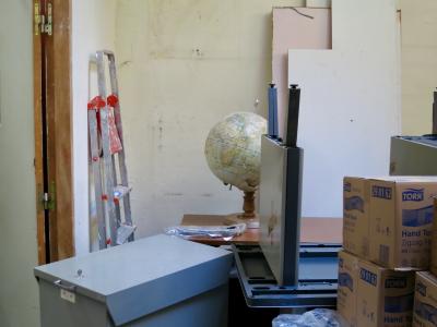 photograph “XII.2012 — Still life with moving administration” par David Farreny — www.farreny.net — France, déménagement, move, moving, bureau, office, bureaux, desks, soviétiques, Soviet, métal, metal, meubles, mobilier, furniture, escabeau, stepladder, pair of steps, globe terrestre, globe, Terre, Earth, administration, public service, cartons, cardboard boxes, Tork, hand towel, porte, door, chambranle, frame, casing, charnières, hinges, clé, key, plaques, contreplaqué, plywood, sheets, plastique, plastic, mur, wall, traces, marks, étiquette, label, K-W, désordre, untidiness, mess, profusion, Occitanie, Aveyron, Rouergue, Rodez