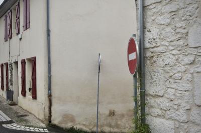 photograph “I.2025” par David Farreny — www.farreny.net — France, Occitanie, Gascogne, Gascony, Gers, Mauvezin, maison, joue, fenêtres, windows, volets, shutters, bois, wood, porte, door, gouttières, drainpipes, métal, metal, mur, wall, pierre, stone, rue, street, ruelle, alley, croisement, crossing, panneaux, signs, routiers, roadsigns, sens interdit, one way, plante, plant, trottoir, pavement, pot, génoises