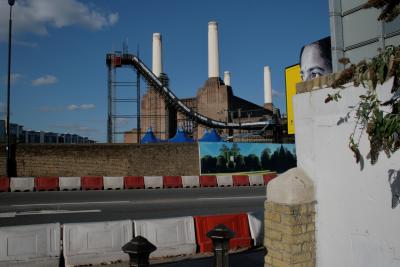 photograph “X.2010 — Battersea hunt, 5” par David Farreny — www.farreny.net — Royaume-Uni, United Kingdom, Angleterre, England, GB, UK, Londres, London, Battersea, Wandsworth, power station, Battersea power station, cheminées, chimneys, brique, brick, usine, factory, industrie, industry, ville, city, paysage, landscape, cityscape, urbain, métal, metal, lampadaire, réverbère, lamp, street, rue, mur, wall, plante, plant, feuilles, leaves, arbre, tree, immeubles, bâtiments, buildings, nuages, clouds, séparateurs de voie, road dividers, rouge, red, blanc, white, relentlessfreeze.com, snowboard, Relentless Freeze Festival, snow, ramp, rampe, neige, glisse, sliding, gliding, poteaux, posts, chapiteau, big top, profusion, billboard, publicité, panneau, ad, femme, woman, yeux, eyes