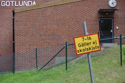 photograph “VIII.2019 — Run away to the North, 269” par David Farreny — www.farreny.net — Suède, Sweden, Sverige, Örebro, Västmanland, Närke, Arboga, Götlunda, ville, city, bourgade, town, école, school, skola, bâtiment, immeuble, building, brique, brick, mur, wall, porte, door, horloge, clock, enseigne, inscription, sign, nom, name, panneau, 7-16 Gäller ej skolskjuts, 7 h-16 h Ne s'applique pas au transport scolaire, 7-16 Does not apply to school transport, clôture, fence, grillage, fencing, métal, metal, herbe, grass, marches, steps, gouttière, drainpipe