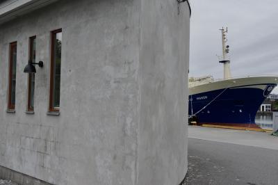 photograph “VI.2019 — Run away to the North, 193” par David Farreny — www.farreny.net — Norvège, Norway, Norge, Hordaland, Austevoll, Bekkjarvik, Selbjørn, île, island, port, harbour, bateau, navire, boat, ship, Manon, pêche, fishing, vaisseau, vessel, métal, metal, acier, steel, eau, water, mer, sea, Selbjørnsfjord, bâtiment, building, béton, concrete, fenêtres, windows, lampe, lamp, angle, coin, corner, bitume, blacktop, asphalt, asphalte, vitre, verre, glass, gris, grey, gray, nuages, clouds