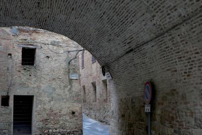 photograph “VIII.2022 — Vicolo remoto, vicolo danesi” par David Farreny — www.farreny.net — Italie, Italia, Italy, Toscane, Toscana, Tuscany, Sienne, Siena, Montepulciano, Vicolo remoto, ruelle distante, remote alley, Vicolo danesi, ruelle danoise, Danish alley, passage, brique, brick, arc, arche, arch, panneau, routier, sign, roadsign, plaques, plates, pierre, stone, bâtiments, buildings, porte, door, fenêtres, windows, câble, cable, fil, wire, volets, shutters, bois, wood, ruelle, alley, rue, street, ville, city