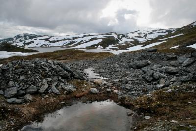photograph “VII.2012 — Run away to the North, 28” par David Farreny — www.farreny.net — Norvège, Norway, Norge, Sogn og Fjordane, Hordaland, Skjelingen, montagne, mountain, rochers, rocks, lac, lake, flaques, puddles, eau, water, cailloux, stones, neige, snow, nuages, clouds, paysage, landscape, herbe, grass, tas, heaps, piles, profusion