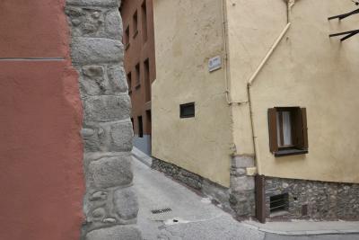 photograph “VI.2022 — Faces of home, 148” par David Farreny — www.farreny.net — Espagne, España, Spain, Catalogne, Cataluña, Catalunya, Catalonia, Gérone, Girona, Baixa Cerdanya, Basse-Cerdagne, Cerdagne, Cerdanya, Puigcerdà, ville, city, rue, street, carrer Vella de l'Estany, bitume, blacktop, asphalte, asphalt, bâtiments, immeubles, buildings, pierre, stone, tuyau, pipe, gouttière, drainpipe, câble, cable, fil, wire, fenêtres, windows, volets, shutters, bois, wood, trottoir, pavement, plaque, plate, angle, coin, corner, domicile, home