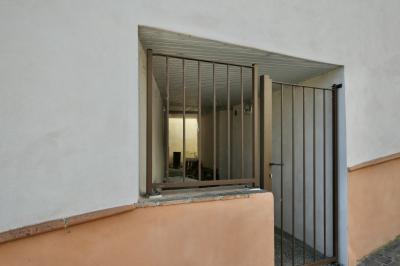 photograph “V.2025” par David Farreny — www.farreny.net — France, Aquitaine, Nouvelle-Aquitaine, Lot-et-Garonne, Astaffort, bâtiment, building, maison, house, passage, couloir, corridor, porte, door, grille, grid, railing, métal, metal, entrée, entrance, poignée, handle, mur, wall, pavés, paving, lampe, lamp, lumière, light, fond, end, dépression, depression