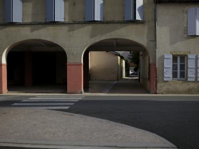 photograph “X.2016” par David Farreny — www.farreny.net — France, village, rue, street, place, square, maisons, houses, arches, archs, fenêtres, windows, volets, shutters, bois, wood, voiture, car, bitume, blacktop, asphalte, asphalt, trottoir, pavement, gouttière, gutter, drainpipe, arbre, tree, Occitanie, Gascogne, Gers, L'Isle-de-Noé