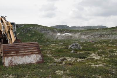 photograph “VIII.2014 — Run away to the North, 84” par David Farreny — www.farreny.net — Norvège, Norway, Norge, Hardangervidda, Buskerud, Hol, plateau, paysage, landscape, rochers, rocks, collines, hills, herbe, grass, vide, empty, emptiness, tractopelle, backhoe, engin, vehicle, pelle, shovel, digger, neige, snow, névé, firn, métal, metal, rouille, rust, rusty