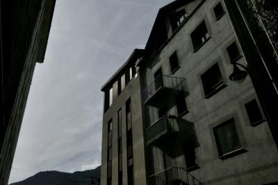 photograph “X.2023 — Faces of home, 189” par David Farreny — www.farreny.net — Andorre, Andorra, Encamp, bâtiment, immeuble, building, béton, concrete, façade, facade, balcons, balconies, fenêtres, windows, lampe, lamp, rue, street, toit, roof, ciel, sky, nuages, clouds, gouttière, drainpipe, métal, metal, pierre, stone, ombres, shadows, câble, cable, fil, wire, montagne, mountain, domicile, home