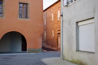 photograph “II.2014 — Veterans” par David Farreny — www.farreny.net — France, rues, streets, maisons, houses, pierre, ciment, cement, fenêtres, windows, ville, town, portes, doors, arche, arch, arc, poignée, handle, bitume, blacktop, asphalte, asphalt, reflet, reflection, verre, vitre, glass, store, volet, shutters, plaque, plate, rue des Anciens-Combattants, coin, corner, angle, trottoir, pavement, goulotte, gouttière, gutter, Occitanie, Aveyron, Rouergue, Réquista