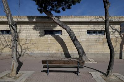 photograph “III.2023” par David Farreny — www.farreny.net — Espagne, España, Spain, Aragón, Aragon, Saragosse, Zaragoza, Caesaraugusta, ville, city, bâtiment, building, banc, bench, trottoir, pavement, dallage, paving, bois, wood, pierre, stone, brique, brick, arbres, trees, troncs, trunks, tordus, twisted, fenêtres, windows, béton, concrete, ciel, sky, ombres, shadows, grilles, rue, street