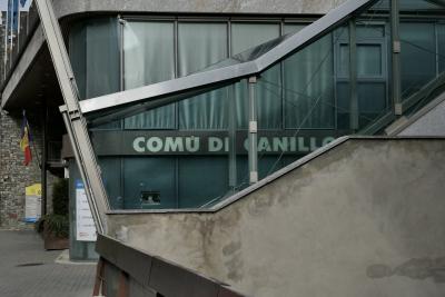 photograph “III.2022” par David Farreny — www.farreny.net — Andorre, Andorra, Canillo, bâtiment, immeuble, building, mairie, city hall, town hall, drapeaux, flags, béton, concrete, métal, metal, escalier, staircase, bois, wood, verre, vitre, glass, fenêtres, baies, windows, enseigne, sign, Comú de Canillo, pierre, stone, rideaux, curtains