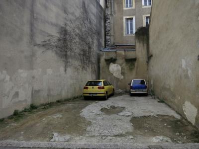 photograph “I.2017 — Parklife” par David Farreny — www.farreny.net — France, parking, car park, voitures, cars, ville, city, immeubles, buildings, bâtiments, fenêtres, windows, lierre, ivy, béton, concrete, ciment, cement, place, emplacement, renfoncement, recoin, recess, nook, murs, walls, gouttière, drainpipe, trou, hole, Occitanie, Gascogne, Gers, Auch