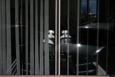 photograph “II.2010 — ∩” par David Farreny — www.farreny.net — France, salon, coiffure, hairdressing, vitrine, window, reflet, reflection, voitures, cars, casques, permanente, hair, dryers, store, shade, shutters, sièges, seats, ∩, intersection, soleil, sun, Occitanie, Aveyron, Rouergue, Rodez