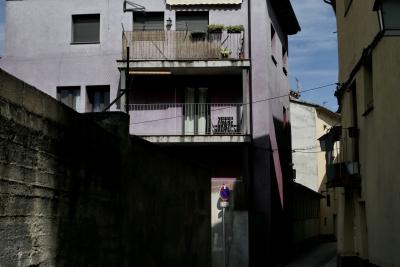 photograph “VIII.2021 — Faces of home, 122” par David Farreny — www.farreny.net — Espagne, Spain, España, Catalogne, Cataluña, Catalunya, Lleida, Lérida, Alt Urgell, La Seu d'Urgell, ville, city, rue, street, immeuble, bâtiment, building, béton, concrete, parpaings, breeze-blocks, balcons, balconies, rambardes, guardrails, câbles, cables, fils, wires, lampe, lamp, fenêtres, windows, panneau, routier, sign, roadsign, grillage, fencing, domicile, home