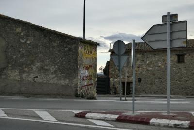 photograph “I.2022 — Nothingness in Pau” par David Farreny — www.farreny.net — Espagne, España, Espanya, Spain, Catalogne, Cataluña, Catalunya, Comarques gironines, Gérone, Gerona, Girona, Alto Ampurdán, Alt Empordà, Pau, route, road, murs, walls, pierre, stone, vieux, old, bitume, blacktop, asphalte, asphalt, panneaux, routiers, signs, roadsigns, métal, metal, toit, roof, tuiles, tiles, hiver, winter, soir, evening, graffitis, nuages, clouds, dépression, depression
