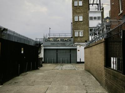 photograph “VIII.2015 — Reach Chelsea” par David Farreny — www.farreny.net — Royaume-Uni, United Kingdom, Angleterre, England, GB, UK, Londres, London, Chelsea, Kensington and Chelsea, ville, city, métal, metal, impasse, dead end, mur, wall, brique, brick, beige, grilles, railings, enseigne, sign, Chelsea Reach, 78/89 Lots Road, bureaux, offices, bâtiment, immeuble, building, store, blind, fenêtres, windows, structure, béton, concrete, escaliers, stairs, staircases, poteaux, posts, ciel, sky, gris, grey, gray, lampes, lamps