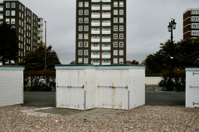 photograph “V.2013” par David Farreny — www.farreny.net — Royaume-Uni, United Kingdom, Grande-Bretagne, Great Britain, Angleterre, England, GB, UK, Sussex, West Sussex, Worthing, front de mer, seafront, plage, beach, galets, pebbles, shingle, cabines, bain, bathing, huts, bois, wood, planches, planks, immeubles, bâtiments, buildings, tours, towers, haie, hedge, arbres, trees, lampadaire, street lamp, brique, brick, fenêtres, windows, bitume, blacktop, asphalte, asphalt, balcons, balconies