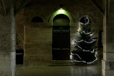 photograph “XII.2019” par David Farreny — www.farreny.net — France, Occitanie, Gascogne, Gers, Jegun, halle, hall, pierre, stone, porte, door, sapin, tree, arbre, Noël, Christmas, guirlande lumineuse, light string, lumières, lights, piliers, pillars, arche, arch, bois, wood