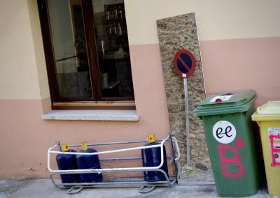 photograph “IX.2021” par David Farreny — www.farreny.net — Andorre, Andorra, Escaldes-Engordany, maison, house, rue, street, bar, fenêtre, window, poubelles, trash, bins, plastique, plastic, gaz, gas, bouteilles, bottles, cylinders, miroir, mirror, verre, vitre, glass, panneau, sign, roadsign, interdiction de stationner, no parking, métal, metal, pierre, stone, ciment, cement, bois, wood, trottoir, pavement
