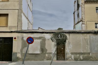 photograph “III.2023” par David Farreny — www.farreny.net — Espagne, España, Spain, Aragon, Aragón, Saragosse, Zaragoza, Utebo, rue, street, bâtiments, immeubles, buildings, trottoir, pavement, fenêtres, windows, porte, door, garage, portail, gate, câbles, cables, fils, wires, arbuste, shrub, arbre, tree, penché, leaning, panneau, sign, routier, roadsign, métal, metal, bois, wood, parallèles, parallels, mur, wall, ciment, cement, toit, roof, tuiles, tiles, démolition, demolition, brique, brick, ciel, sky