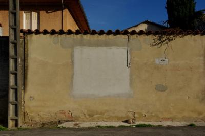 photograph “XI.2015 — Tonight on your screens” par David Farreny — www.farreny.net — France, mur, wall, jaune, yellow, rectangle, carré, square, gris, grey, gray, chat, cat, endormi, sleeping, ciment, cement, tuiles, tiles, poteau, post, pole, électrique, electricity, maison, house, fenêtre, window, volets, shutters, arbre, tree, cyprès, cypress, béton, concrete, gouttière, drainpipe, câble, wire, fil, cable, toits, roofs, animal, rue, street, bitume, blacktop, asphalte, asphalt, Occitanie, Gascogne, Gascony, Gers, Vic-Fezensac