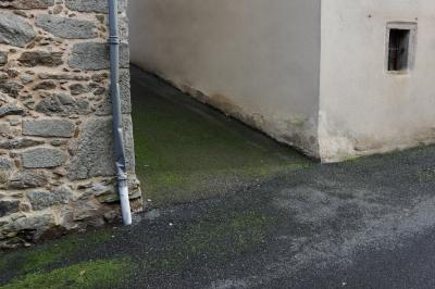 photograph “I.2015” par David Farreny — www.farreny.net — France, Occitanie, Aveyron, Rouergue, Rieupeyroux, rue, street, bitume, blacktop, asphalte, asphalt, humidité, dampness, mousse, moss, gouttière, drainpipe, métal, metal, pierre, stone, angle, coin, corner, fenêtre, window, hiver, winter