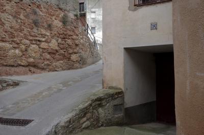 photograph “XI.2021 — Faces of home, 153” par David Farreny — www.farreny.net — Espagne, España, Espanya, Spain, Catalogne, Cataluña, Catalunya, Catalonia, Lérida, Lleida, Alt Urgell, Coll de Nargó, bourgade, town, village, ruelle, alley, rue, street, old, vieux, pierre, stone, maison, house, mur, wall, garage, portail, gate, entrée, entrance, entry, plaque, plate, numéro, number, 24, fenêtres, windows, domicile, home