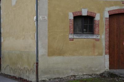 photograph “XI.2015” par David Farreny — www.farreny.net — France, Occitanie, Gascogne, Gers, Jegun, place du Foirail, chemin de Roses, bâtiment, building, mur, wall, gouttière, drainpipe, fenêtre, window, portail, gate, garage, jaune, yellow, beige, métal, metal, brique, brick, bois, wood, pierre, stone, angle, coin, corner, herbe, grass, arche, arch, arc, plaques, plates, foirail, fairground