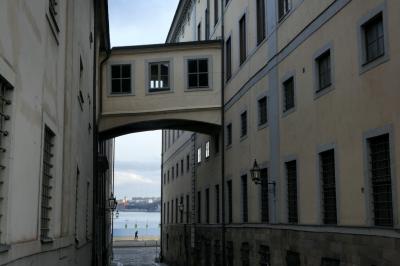 photograph “II.2022 — Run away to the North, 215” par David Farreny — www.farreny.net — Suède, Sverige, Sweden, Uppland, Södermanland, Stockholm, ville, city, capitale, capital, immeubles, bâtiments, buildings, ruelle, alley, rue, street, Gamla Stan, fenêtres, windows, eau, water, Strömmen, lampe, lamp, rive, shore, coureur, runner, sportif, sportsman, grilles, railings, hiver, winter
