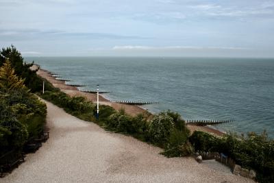 photograph “VII.2010” par David Farreny — www.farreny.net — Royaume-Uni, United Kingdom, Angleterre, England, GB, UK, Sussex, Eastbourne, paysage, landscape, Manche, Channel, mer, sea, côte, coast, plage, beach, horizon, nuages, clouds, arbres, trees, massif, arbustes, shrubberies, lampadaires, lamps, gravier, gravel, chemin, path, épis, groynes, brise-lames, breakwaters, seascape