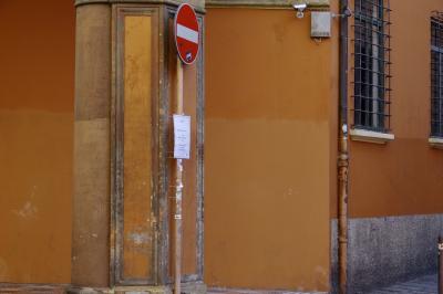 photograph “X.2019” par David Farreny — www.farreny.net — Italie, Italia, Italy, Émilie-Romagne, Emilia-Romagna, Bologne, Bologna, ville, city, bâtiment, immeuble, murs, walls, rue, street, angle, coin, corner, orange, fenêtres, windows, grilles, railings, gouttière, drainpipe, métal, metal, poteau, post, pole, panneau, routier, sign, roadsign, sens interdit, no way, affiche, poster, caméras, vidéo, video, cams, cameras, autocollants, stickers, crépi, roughcast