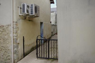 photograph “III.2021 — Faces of home, 120” par David Farreny — www.farreny.net — France, Occitanie, Gascogne, Gers, Éauze, rue, street, ville, city, coin, corner, angle, mur, wall, pierre, stone, enduit, roughcast, gouttière, drainpipe, métal, metal, porte, door, portail, gate, boîtiers, units, climatisation, air conditioning, chauffage, heating, entrée, entrance, maison, house, toit, roof, passage, domicile, home, bleu, blue, jaune, yellow, beige
