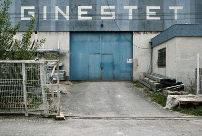 photograph “VI.2012” par David Farreny — www.farreny.net — France, Occitanie, Aveyron, Rouergue, Onet-le-Château, industrie, industry, entreprise, company, entrepôt, warehouse, façade, facade, béton, concrete, métal, metal, clôture, fence, portail, gate, porte, door, fenêtre, window, entrée, entry, entrance, enseigne, sign, nom, name, Ginestet, cale, wedge, bois, wood, rail, track, bleu, blue, fil, wire, câble, cable