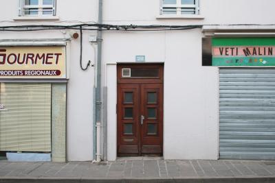 photograph “III.2012 — Faces of home, 53” par David Farreny — www.farreny.net — France, Occitanie, Aveyron, Rouergue, Rodez, immeuble, bâtiment, building, maison, house, rue, street, trottoir, pavement, pierre, stone, mur, wall, porte, door, bois, wood, plaque, plate, numéro, number, 20, fenêtres, windows, volets, shitters, poignée, handle, métal, metal, câbles, cables, fils, wires, gouttière, drainpipe, magasins, shops, boutiques, stores, enseignes, signs, Gourmet, produits régionaux, regional products, Vêti Malin, vêtements, clothes, clothing, rideau, curtain, dimanche, Sunday, closed, haut-parleur, loudspeaker, domicile, home