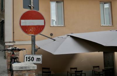 photograph “VIII.2022” par David Farreny — www.farreny.net — Italie, Italia, Italy, Toscane, Toscana, Tuscany, Sienne, Siena, Montepulciano, panneau, routier, sign, roadsign, sens interdit, one way, métal, metal, disque, disc, vélo, bike, bâtiment, immeuble, building, brique, brick, parasols, umbrellas, chaises, chairs, tables, bar, café, restaurant, 150 m, fenêtres, windows, verre, vitre, glass, reflet, reflection, toile, cloth, ombre, shadow