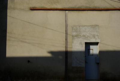 photograph “XI.2015” par David Farreny — www.farreny.net — France, entrepôt, warehouse, mur, wall, ciment, cement, porte, door, métal, metal, câbles, cables, fils, wires, ombre, shadow, automne, autumn, fall, Occitanie, Gascogne, Gascony, Gers, Vic-Fezensac
