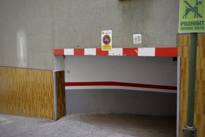 photograph “IX.2021 — Gossos solts” par David Farreny — www.farreny.net — Andorre, Andorra, Andorre-la-Vieille, Andorra la Vella, ville, city, capital, capitale, immeuble, building, bâtiment, béton, concrete, garage, mur, paroi, wall, carreaux, tiling, passage, bas, low, trottoir, pavement, panneau, sign, Prohibit gossos solts, interdit aux chiens seuls, lonely dogs forbidden, poteau, post, pole, chien, dog