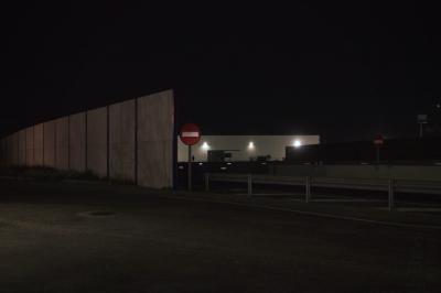 photograph “III.2023 — At night” par David Farreny — www.farreny.net — Espagne, España, Spain, Aragon, Aragón, Saragosse, Zaragoza, Ribera Alta del Ebro, Pedrola, nuit, night, obscurité, darkness, noir, black, mur, wall, béton, concrete, glissière de sécurité, crash barrier, métal, metal, panneau, sign, routier, roadsign, sens interdit, one way, no entry, entrepôt, warehouse, lumières, lights, route, road, bitume, blacktop, asphalte, asphalt, ombre, shadow