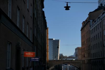 photograph “II.2022 — Run away to the North, 222” par David Farreny — www.farreny.net — Suède, Sverige, Sweden, Uppland, Södermanland, Stockholm, ville, city, capitale, capital, rue, street, bâtiments, immeubles, buildings, tour, tower, lampes, lamps, enseignes, signs, magasins, shops, Som Du Vill, Dogga Design, fenêtres, windows, ciel, sky, pont, bridge, câbles, cables