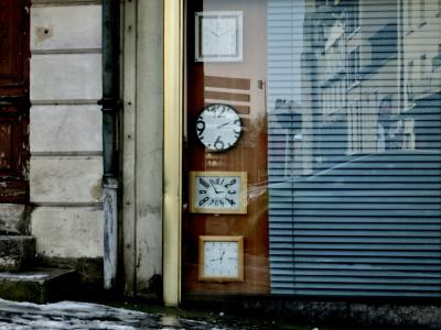 photograph “II.2012 — Tempus fugit” par David Farreny — www.farreny.net — France, Occitanie, Aveyron, Rouergue, Rodez, ville, city, rue, street, hiver, winter, neige, snow, trottoir, pavement, magasin, shop, store, horlogerie, horloges, clocks, temps, time, vitrine, window, bay, verre, vitre, glass, store, porte, door, marches, steps, reflet, reflection, voiture, car, immeubles, buildings, bâtiments, aiguilles, hands, nombres, numbers, gouttière, drainpipe, métal, metal