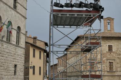 photograph “VIII.2022” par David Farreny — www.farreny.net — Italie, Italia, Italy, Toscane, Toscana, Tuscany, Sienne, Siena, Montepulciano, piazza Grande, bâtiments, buildings, pierre, stone, brique, brick, toits, roofs, tuiles, tiles, drapeaux, flags, fenêtres, windows, cloche, bell, échafaudage, scaffolding, projecteurs, floodlights, métal, metal, échelle, ladder, volets, shutters, bois, wood, lampe, lamp