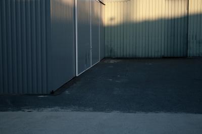 photograph “XII.2011” par David Farreny — www.farreny.net — France, zone industrielle, industrial, park, estate, industrie, industry, soir, evening, hiver, winter, tôle ondulée, corrugated iron, bitume, blacktop, asphalte, asphalt, portail, gate, métal, metal, Occitanie, Rouergue, Aveyron, Olemps