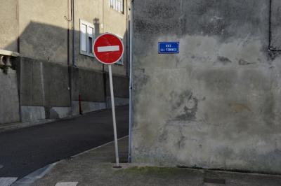 photograph “X.2015” par David Farreny — www.farreny.net — France, Occitanie, Gascogne, Gascony, Gers, Vic-Fezensac, ville, city, bourgade, town, rue, street, plaque, rue des Femmes, panneau, sign, roadsign, sens interdit, one way, mur, wall, ciment, cement, fenêtres, windows, bitume, blacktop, asphalte, asphalt, gouttière, drainpipe, métal, metal, câble, cable, fil, wire, angle, coin, corner, trottoir, pavement