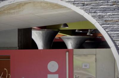 photograph “IV.2023 — Fora de servei” par David Farreny — www.farreny.net — Andorre, Andorra, Canillo, parking, car park, souterrain, underground, arche, arch, arc, pierre, stone, plafond, ceiling, toilettes, toilets, WC, fora de servei, hors service, out of order, porte, door, metal, métal, béton, concrete, logo, affichette, poster, piliers, pillards, lampes, lamps, néon, neon, poignée, handle, tuyau, pipe