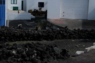 photograph “II.2018 — Lancerotte, 55” par David Farreny — www.farreny.net — Espagne, España, Spain, Canaries, Canarias, Canary, Lanzarote, Lancerotte, maisons, houses, blanches, white, lave, lava, noir, black, rochers, rocks, porte, door, bleu, blue, portail, gate, garage, métal, metal, terrasse, terrace, chat, cat, animal, marches, steps, fenêtres, windows, bois, wood, rampe, ramp, gravier, gravel, architecture, profusion, El Golfo, village