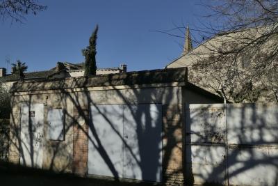 photograph “XII.2023 — Whatever” par David Farreny — www.farreny.net — France, Occitanie, Tarn-et-Garonne, Caussade, garage, portails, gates, métal, metal, mur, wall, brique, brick, arbres, trees, branches, branchages, ombre, shadow, cyprès, cypress, clocher, bell tower, église, church, maisons, houses, toits, roofs