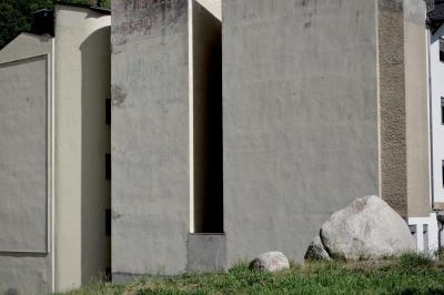 photograph “IX.2021 — Faces of home, 128” par David Farreny — www.farreny.net — Andorre, Andorra, Escaldes-Engordany, immeuble, building, bâtiment, béton, concrete, mur, wall, publicité, pub, advertising, ad, vieux, old, angles, coins, corners, rochers, rocks, herbe, grass, fenêtres, windows, crépi, roughcast, gouttière, drainpipe, ville, city, laid, ugly, laideur, ugliness, domicile, home