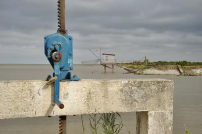 photograph “VII.2015” par David Farreny — www.farreny.net — France, Aquitaine, Gironde, Jau-Dignac-et-Loirac, port de Richard, port, harbour, harbor, estuaire, estuary, eau, water, pêche, fishing, cabane, pilotis, carrelet, hut, stilts, filet, net, bois, wood, béton, concrete, métal, metal, rouille, rust, rusty, cadenas, lock, poignée, handle, horizon, nuages, clouds, rivage, shore